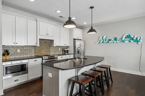 a kitchen with kitchen island granite countertop a stove a sink a counter space and cabinets