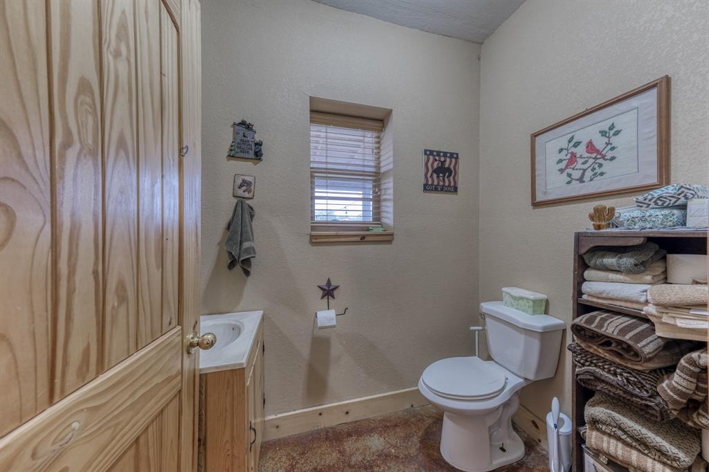 2975 North Fm 1702 Hamilton, TX 76531 - Photo 14 of 35 a white toilet sitting next to a bathroom sink and vanity