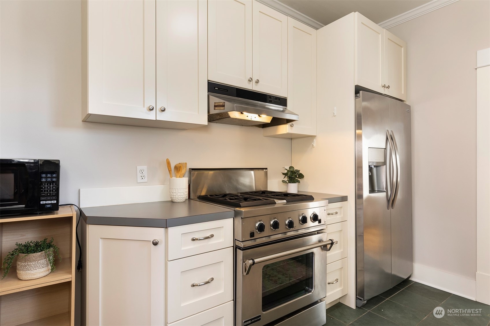 110 North 76th Street Seattle, WA 98103 - Photo 15 of 36 a kitchen with white cabinets and stainless steel appliances