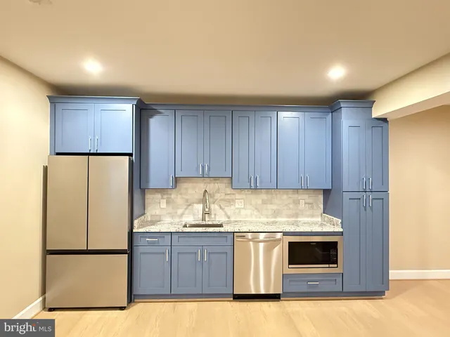 a kitchen with granite countertop a refrigerator sink and cabinets