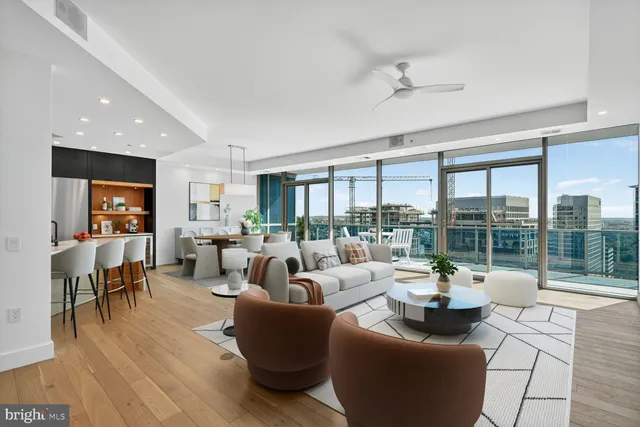 a living room with furniture large windows and wooden floor