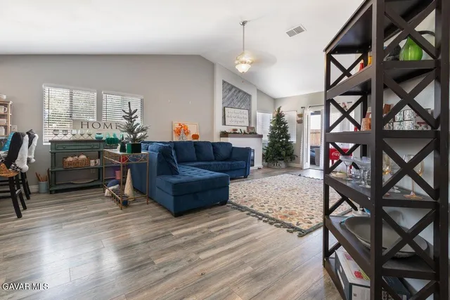 a living room with a couch and a dining table with wooden floor
