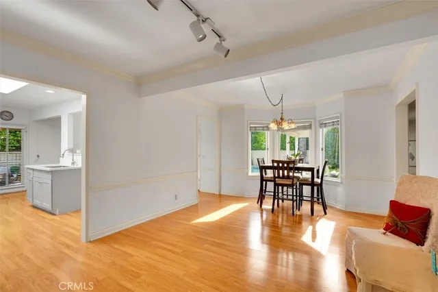 a dining room with wooden floor a chandelier a glass table and chairs