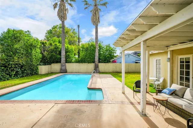 a view of a patio with a table chairs potted plants and palm trees