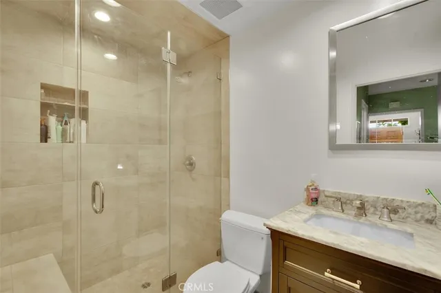 a bathroom with a granite countertop sink toilet a mirror and shower