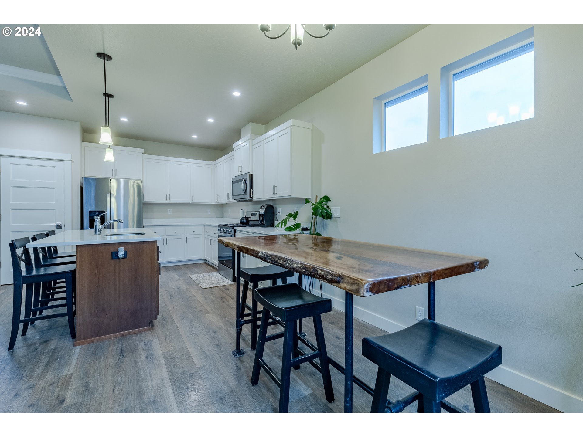 1026 West Olympic Street Springfield, OR 97477 - Photo 7 of 31 a kitchen with stainless steel appliances kitchen island a table chairs in it and wooden floor