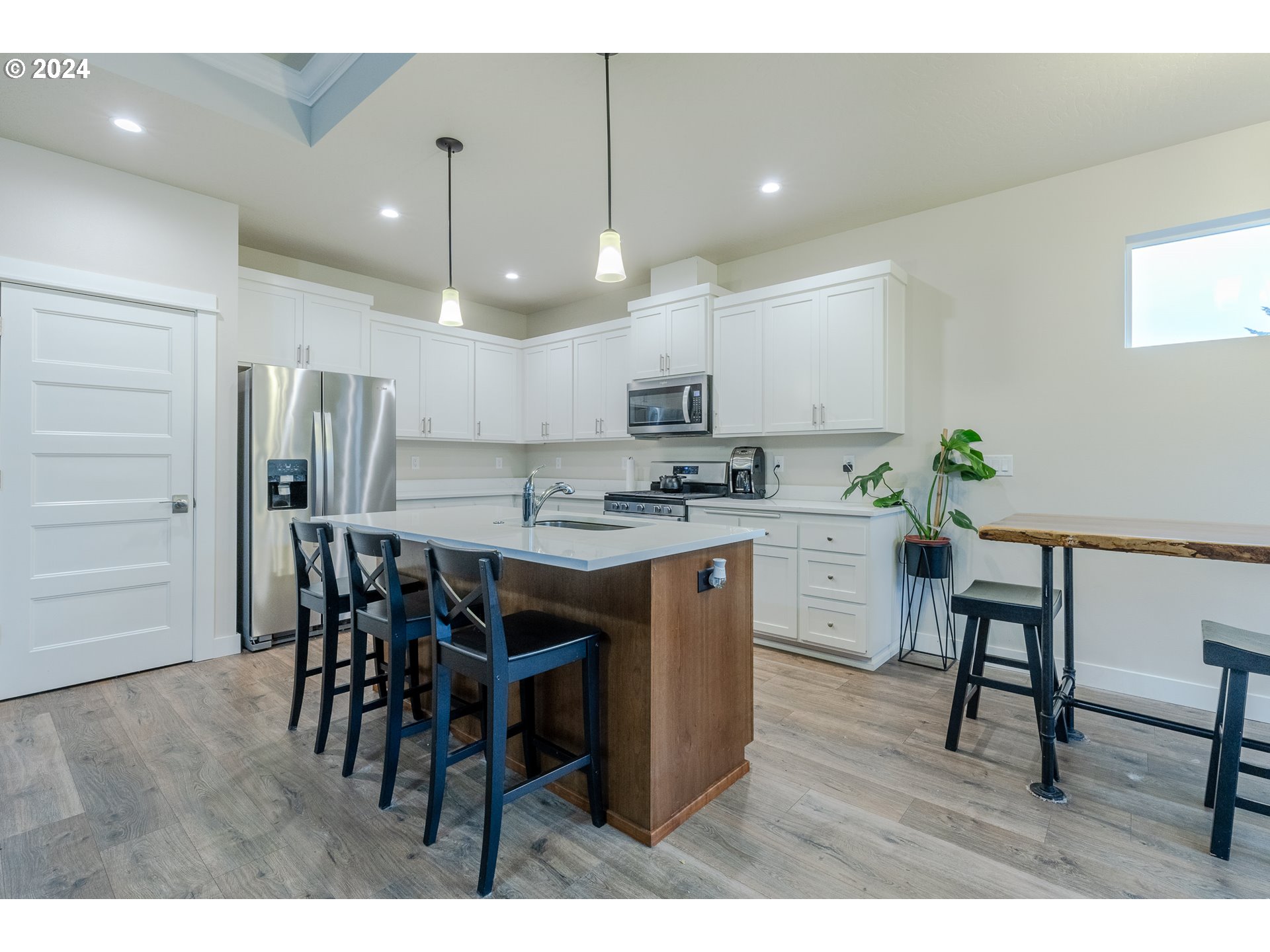 1026 West Olympic Street Springfield, OR 97477 - Photo 8 of 31 a kitchen with kitchen island granite countertop a table chairs a sink a refrigerator and a stove