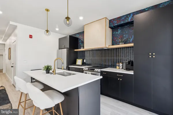 a kitchen with a sink a stove a refrigerator and chairs