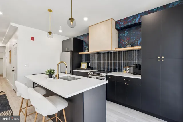 a kitchen with a sink a stove a refrigerator and chairs