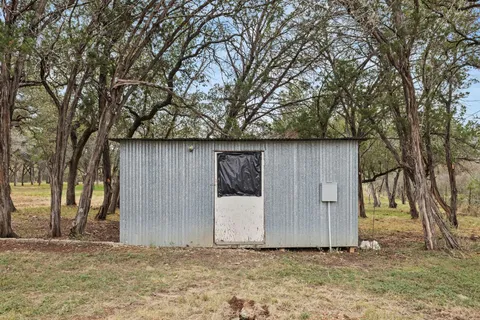 a backyard of a house with large trees and wooden fence