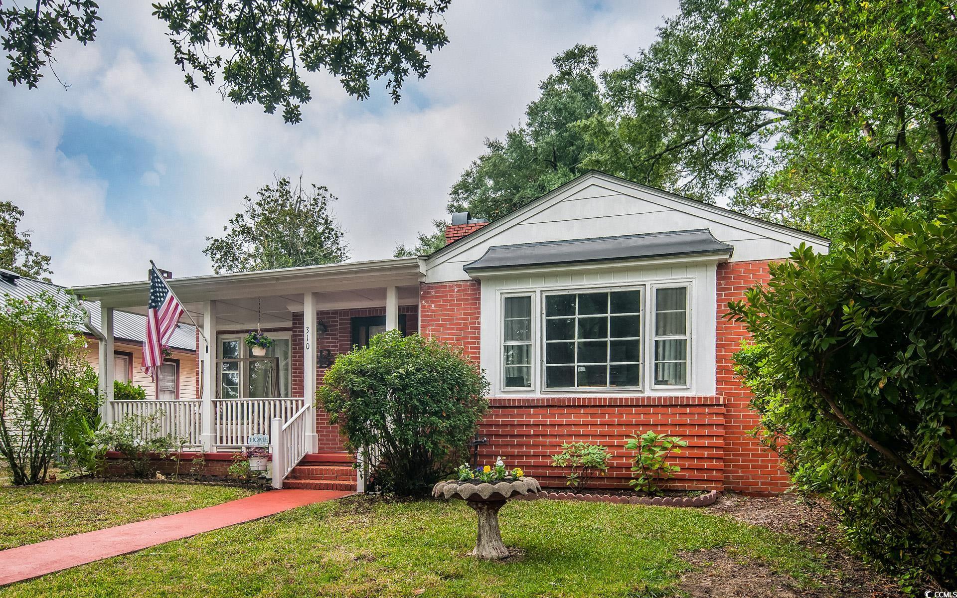 310 St James Street Georgetown, SC 29440 - Photo 2 of 25 View of front of house with brick siding, a front lawn, a chimney, and a porch