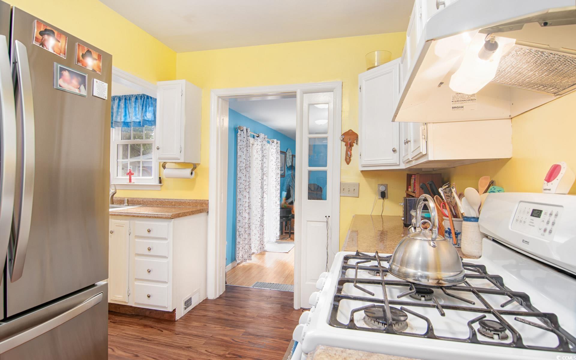 310 St James Street Georgetown, SC 29440 - Photo 10 of 25 Kitchen with white cabinetry, freestanding refrigerator, white range with gas cooktop, extractor fan, and dark wood-style flooring