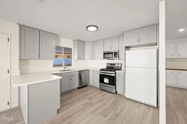 a kitchen with refrigerator a stove top oven and white cabinets