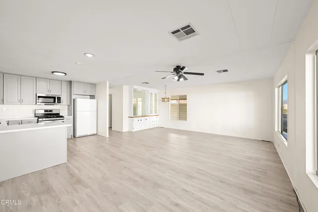 an empty room with wooden floor ceiling fan and windows