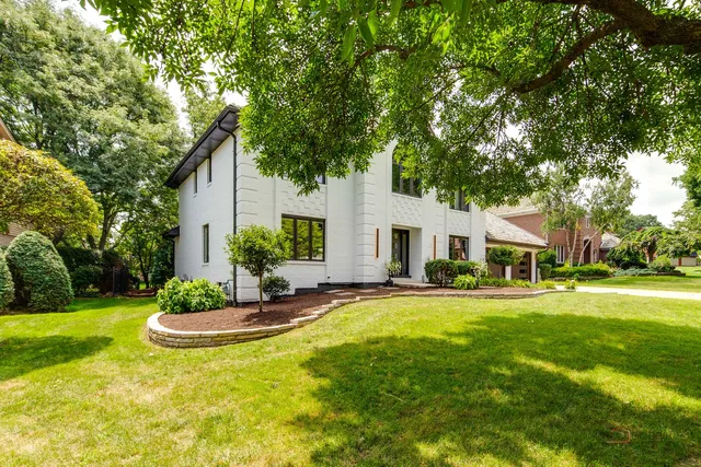 a view of a white house in a big yard with palm trees