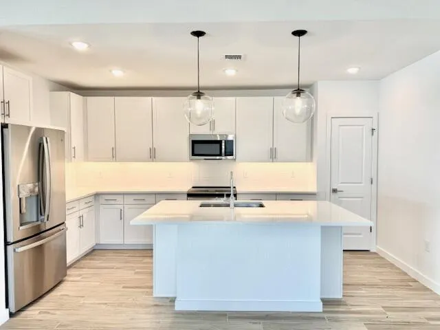 a kitchen with kitchen island a counter space a sink appliances and cabinets