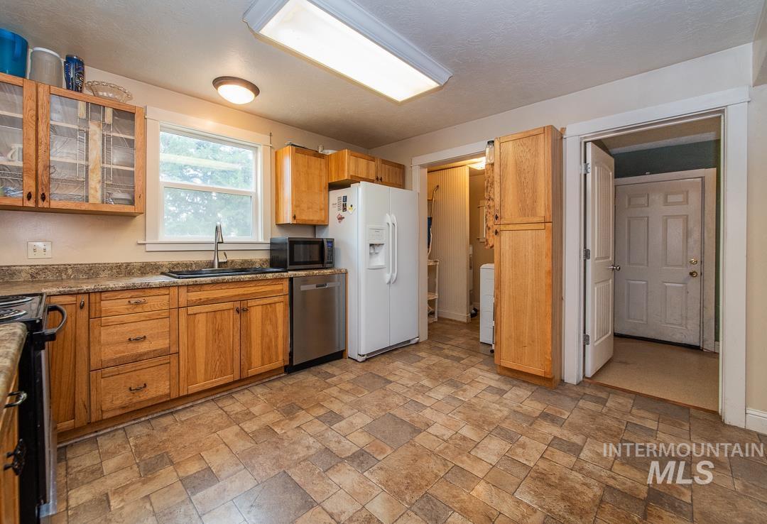 595 Cemetery Road Cambridge, ID 83610 - Photo 13 of 47 Kitchen featuring wood cabinetry, stone-look countertops, and a stainless steel dishwasher