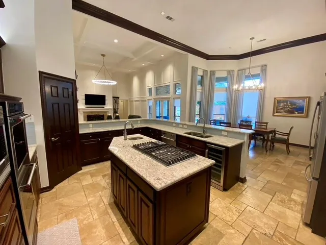 a kitchen with kitchen island granite countertop a stove a sink dishwasher and a refrigerator with wooden floor