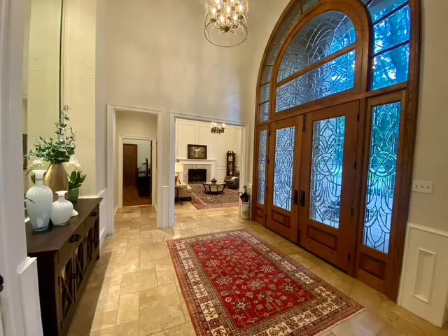 a hallway with a chandelier and a rug