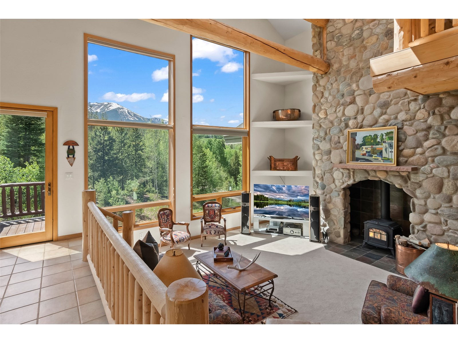1746 South Ruby Road Silverthorne, CO 80498 - Photo 21 of 50 Carpeted living room featuring a stone fireplace, a wealth of natural light, and a wood stove