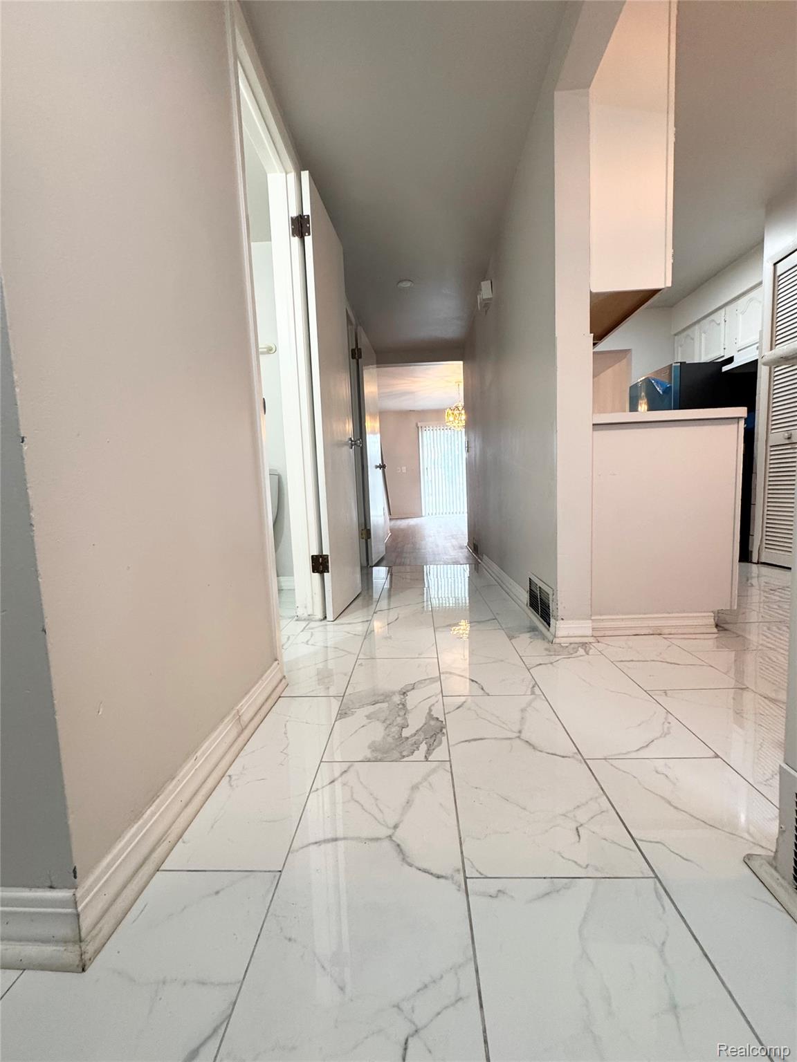 4386 15 Mile Road, Unit 64 Sterling Heights, MI 48310 - Photo 14 of 23 Hallway featuring large format marble-look tile flooring, white baseboards, and light-toned walls