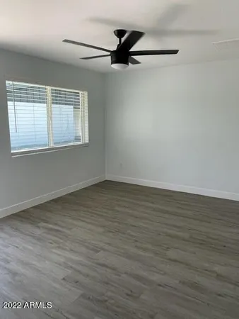 an empty room with wooden floor and a ceiling fan