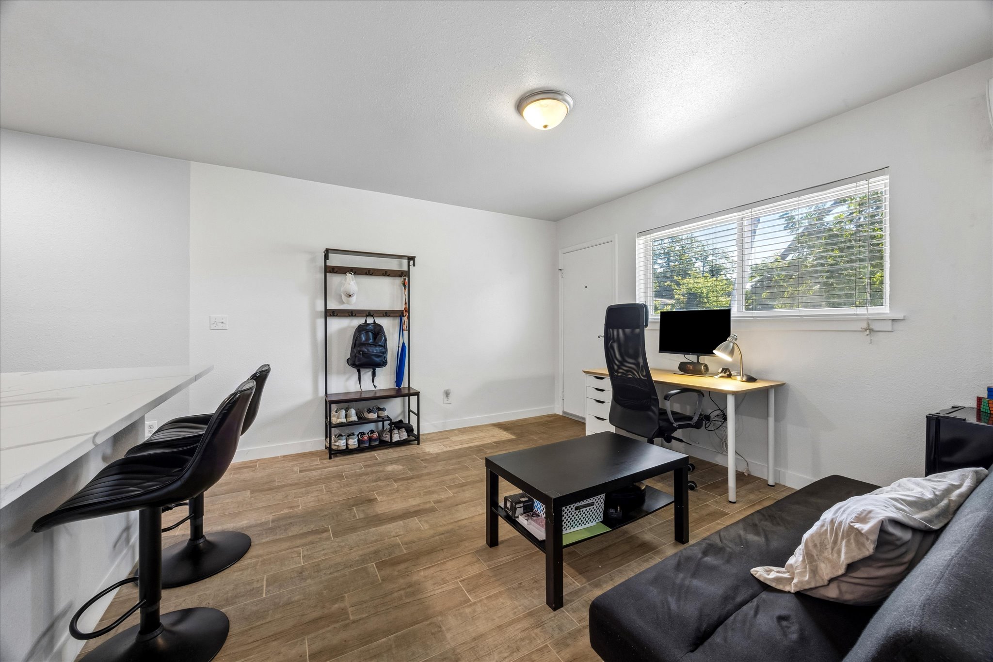 304 East 33rd Street, Unit 4 Austin, TX 78705 - Photo 3 of 15 Open-concept living room featuring light wood-look porcelain tile flooring, fresh paint white walls, and a large window with white 2" blinds