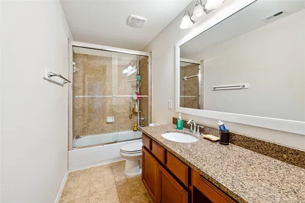 a bathroom with a granite countertop sink a toilet a mirror and shower