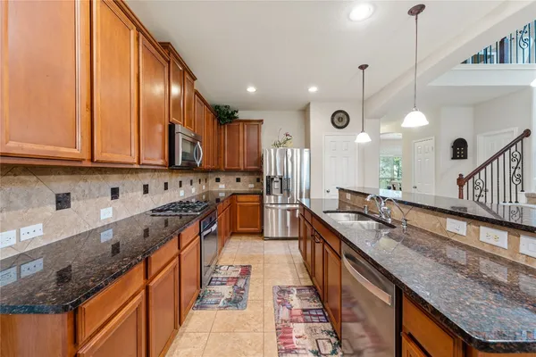 a kitchen with stainless steel appliances granite countertop a sink a stove and a wooden floors