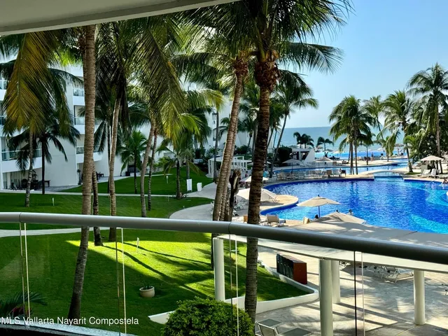 a view of swimming pool with a yard and palm trees