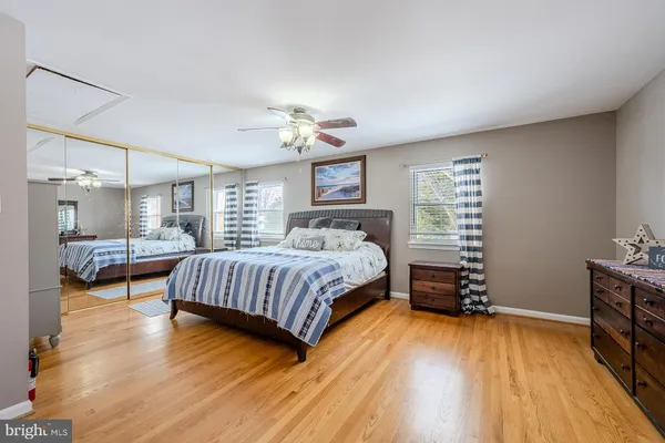 a bedroom with a bed and dresser with wooden floor