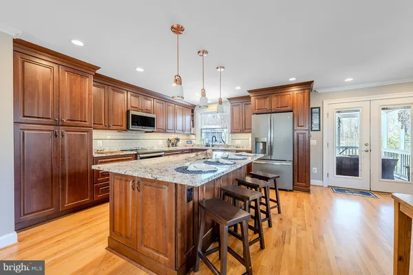 a kitchen with stainless steel appliances granite countertop a refrigerator a stove and a wooden floors