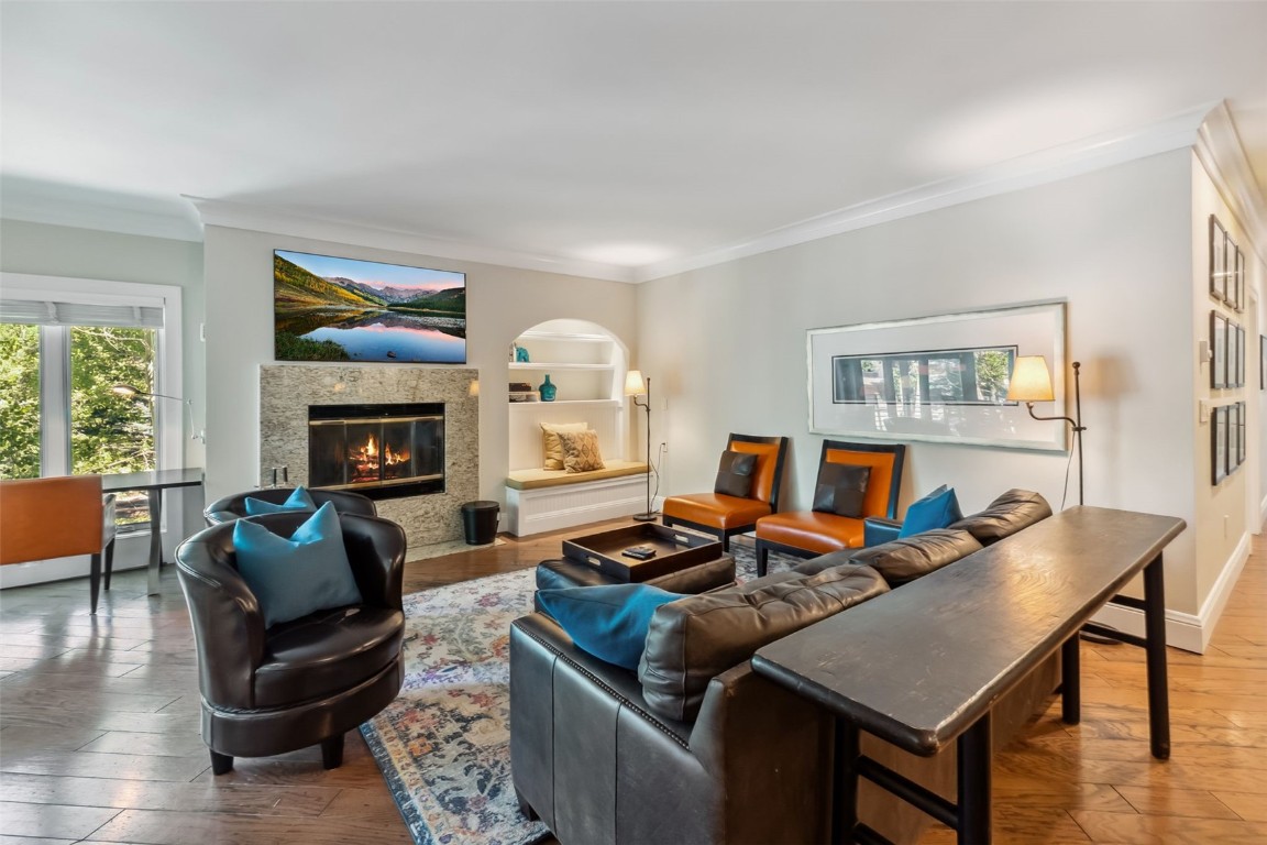 Living room featuring crown molding, a premium fireplace, and wood-type flooring