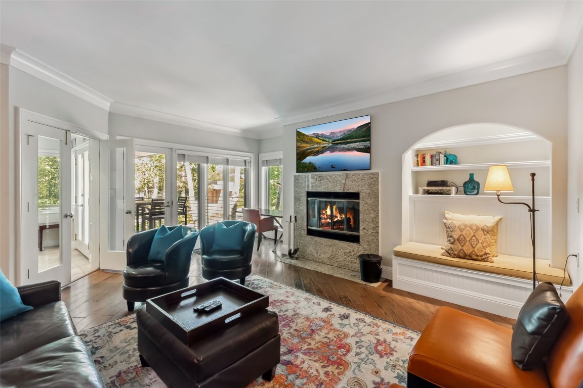 Living room featuring crown molding, healthy amount of natural light, a fireplace, and wood finished floors