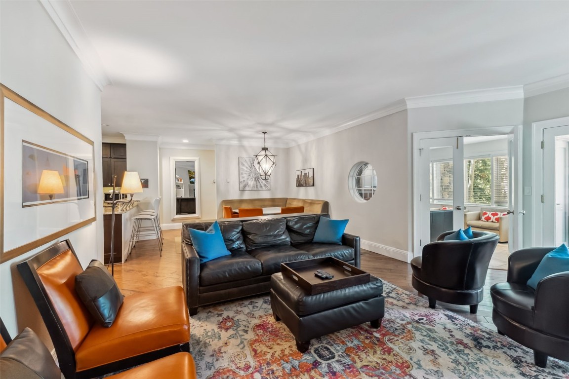 Living room with ornamental molding, a chandelier, and light wood-style flooring