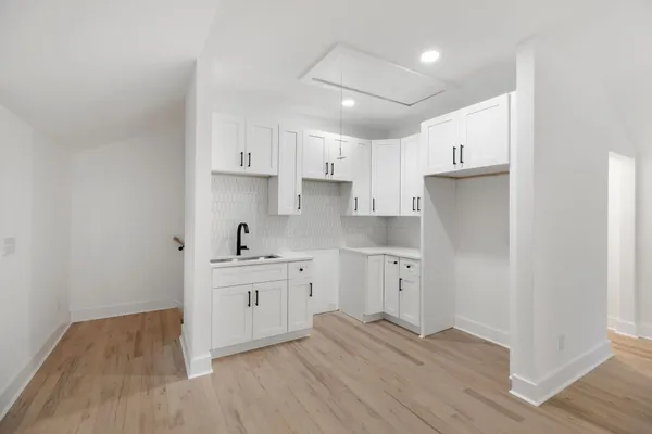 a kitchen with cabinets wooden floor and stainless steel appliances