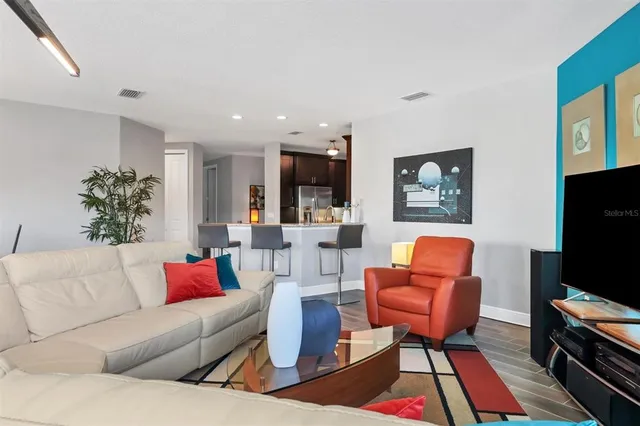 a living room with furniture a kitchen view and a potted plant