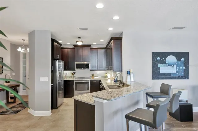 a kitchen with stainless steel appliances granite countertop a sink stove refrigerator and cabinets