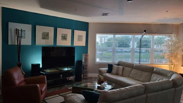 a living room with furniture a flat screen tv and a wall painting