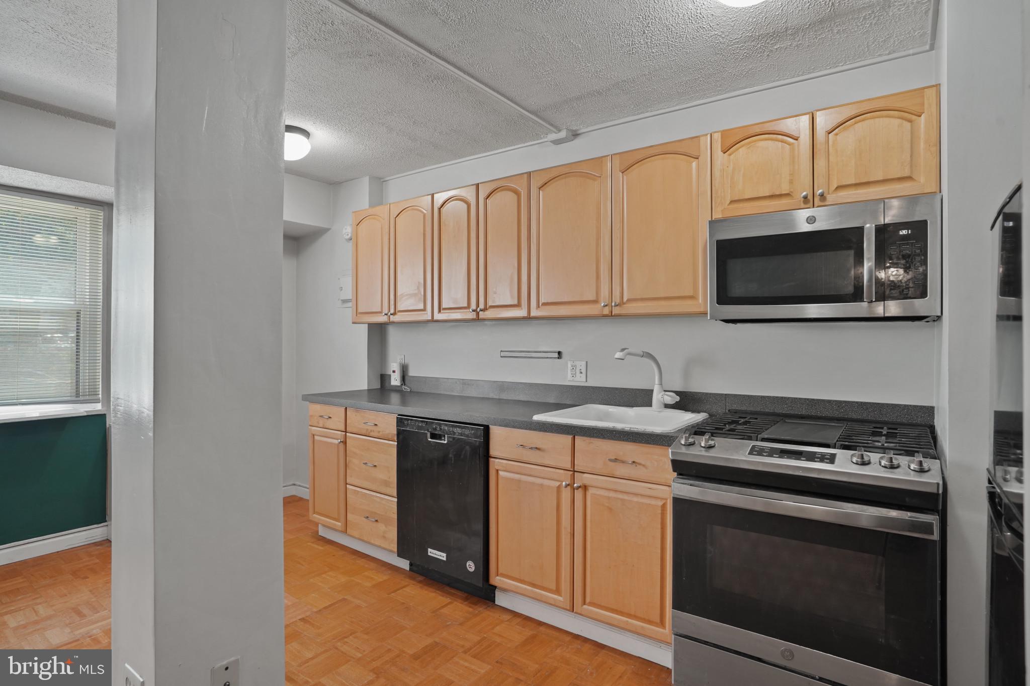 1801 Clydesdale Place Northwest, Unit 420 Washington, DC 20009 - Photo 9 of 33 a kitchen with stainless steel appliances granite countertop a stove microwave and sink