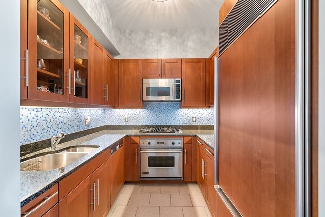 a kitchen with granite countertop stainless steel appliances a sink stove and cabinets
