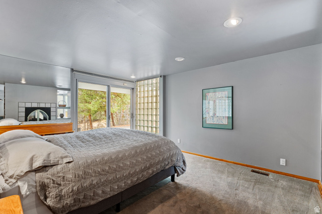 1856 Fort Canyon Road Alpine, UT 84004 - Photo 33 of 49 Sliding glass doors opening to the exterior, recessed ceiling lighting, gray walls, light gray carpeting, and a built-in tiled fireplace with an arched opening