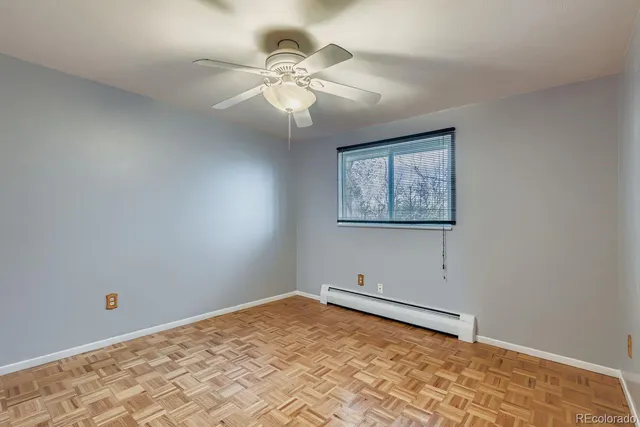 an empty room with a fan & a window