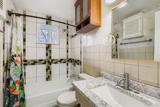 a bathroom with a granite countertop sink a toilet and shower