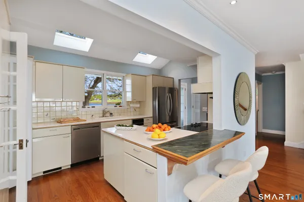 a kitchen with stainless steel appliances granite countertop a stove a sink dishwasher and a refrigerator with wooden floor