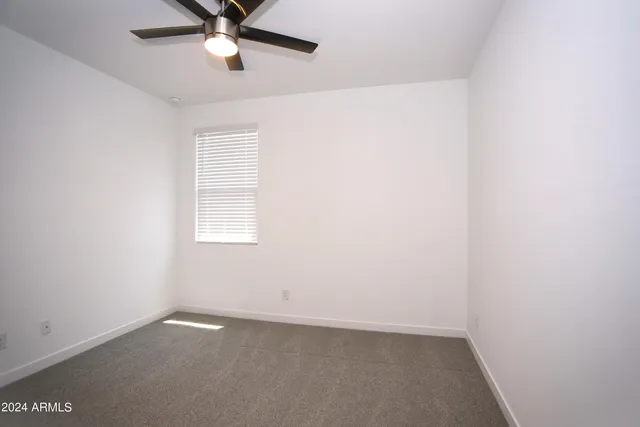 an empty room with a window and a fan