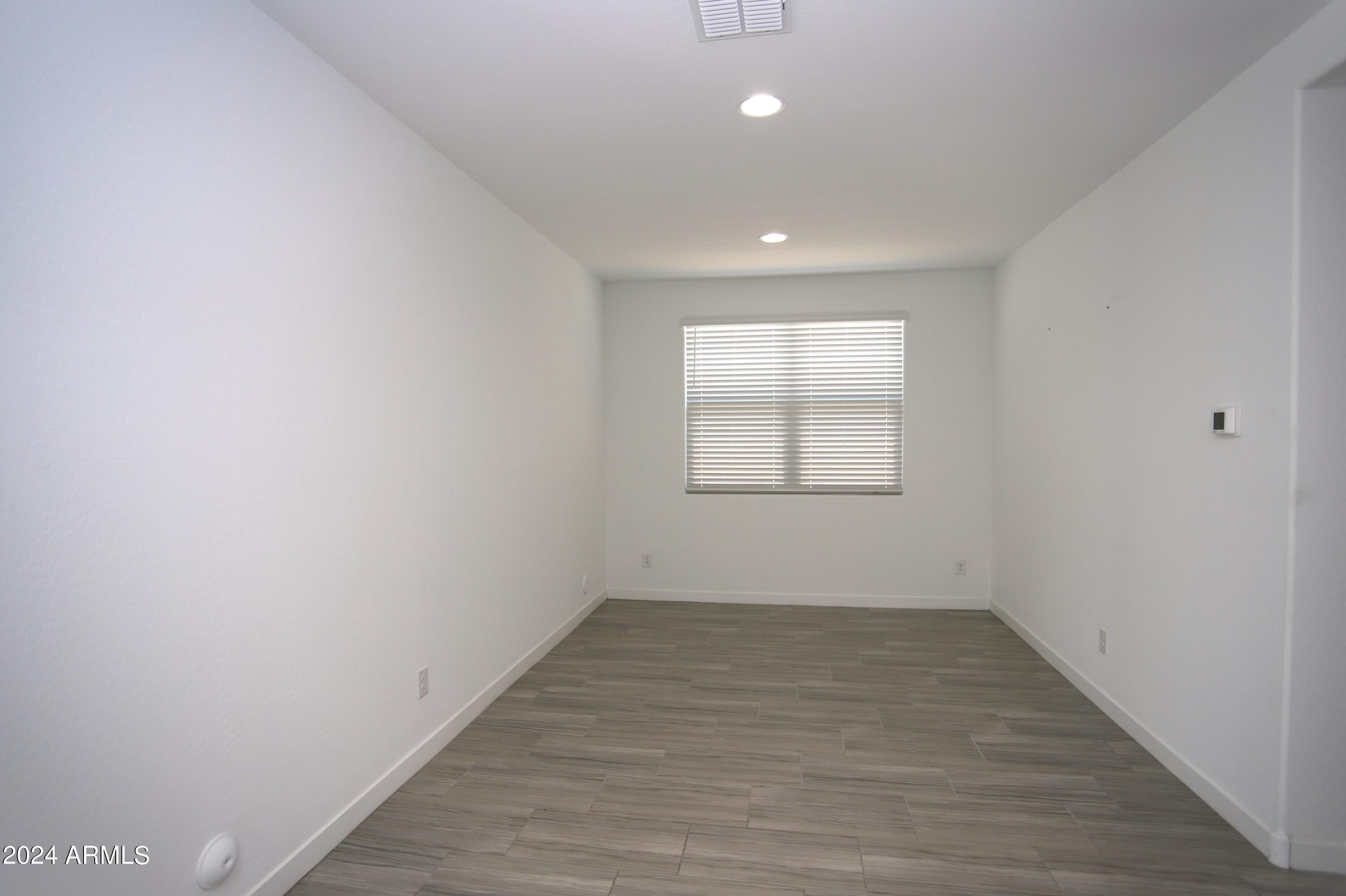 1651 West Piedmont Road Phoenix, AZ 85041 - Photo 17 of 46 an empty room with wooden floor and windows