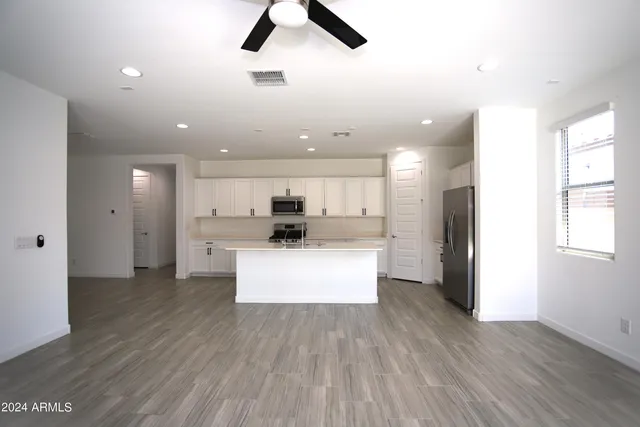 a view of kitchen with kitchen island stainless steel appliances refrigerator stove microwave and cabinets