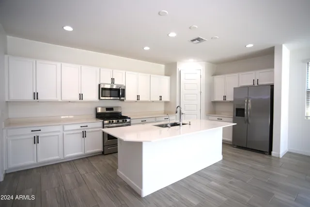 a kitchen with stainless steel appliances granite countertop a stove top oven a refrigerator a sink and dishwasher with wooden floor