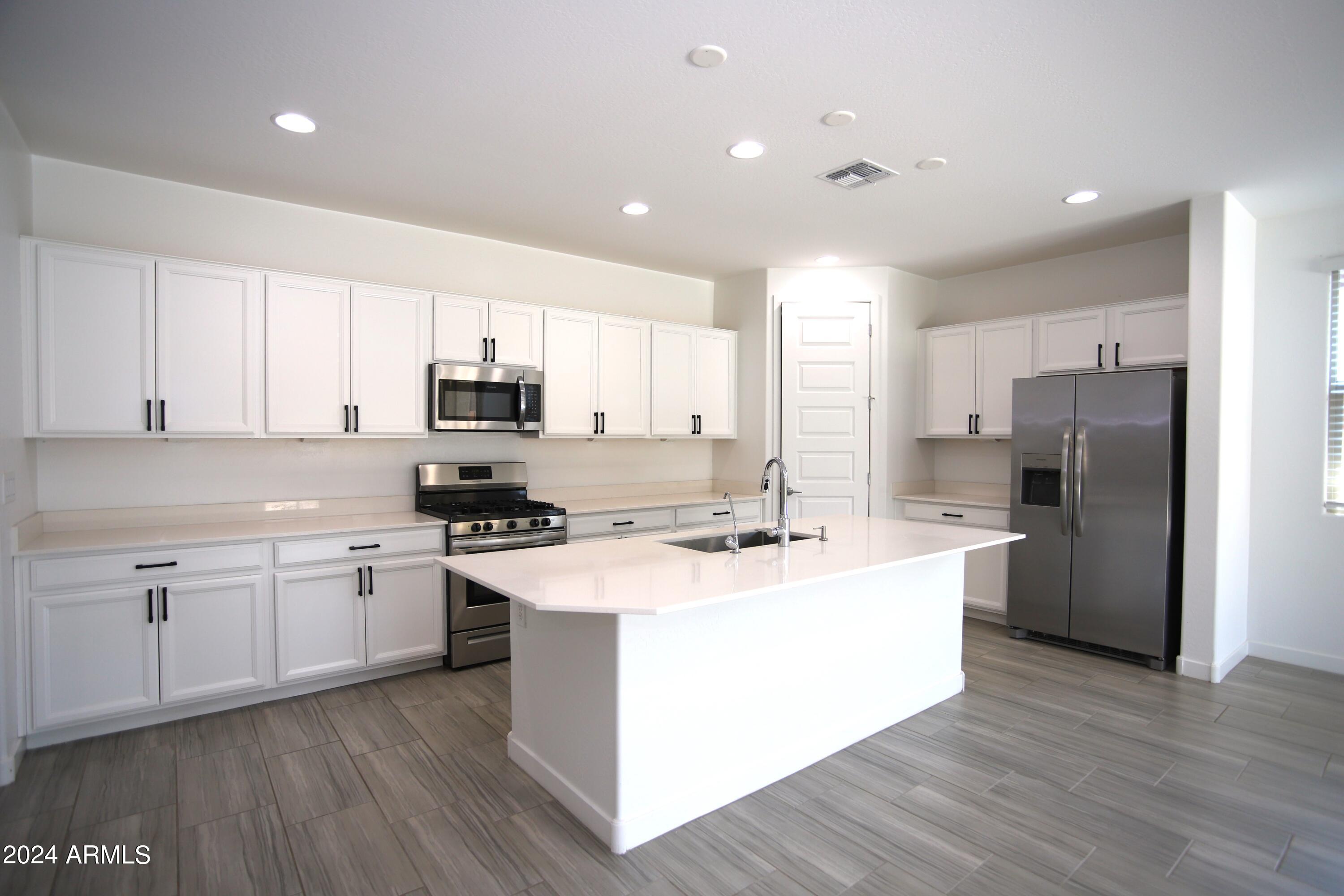 1651 West Piedmont Road Phoenix, AZ 85041 - Photo 21 of 46 a kitchen with stainless steel appliances granite countertop a stove top oven a refrigerator a sink and dishwasher with wooden floor